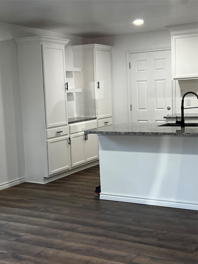 kitchen featuring dark stone countertops, dark hardwood / wood-style floors, sink, and white cabinetry