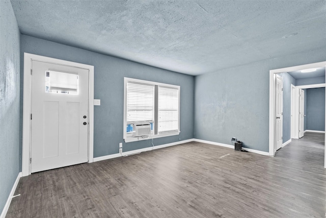 entryway with cooling unit, a textured ceiling, baseboards, and wood finished floors