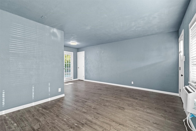 unfurnished room featuring heating unit, baseboards, and wood finished floors