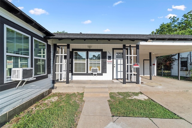 property entrance featuring covered porch, cooling unit, and a shingled roof