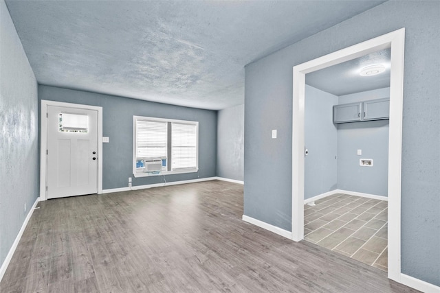 unfurnished living room featuring baseboards, a textured ceiling, and wood finished floors