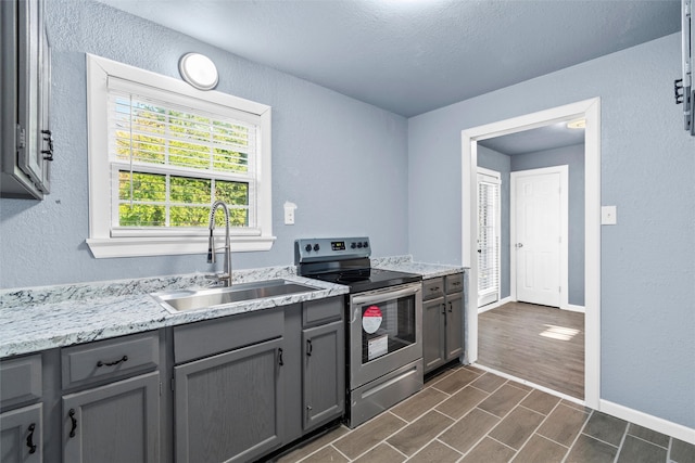 kitchen featuring gray cabinetry, electric stove, dark hardwood / wood-style flooring, and sink