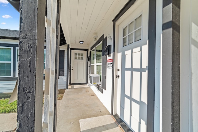 view of exterior entry featuring a porch and cooling unit