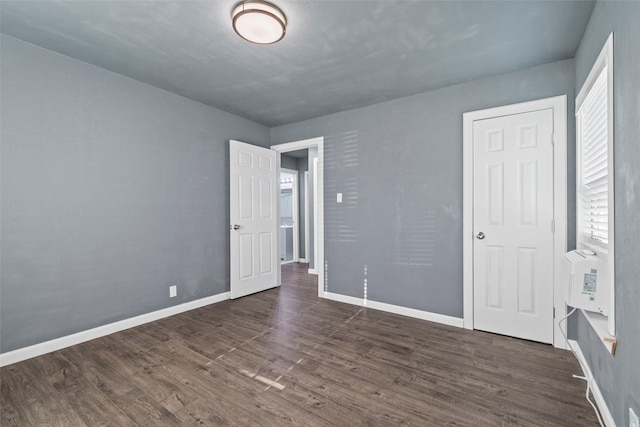 unfurnished bedroom with baseboards and dark wood finished floors