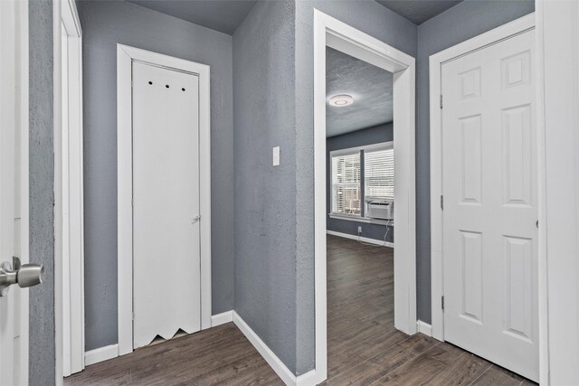 corridor with cooling unit, baseboards, dark wood-style floors, and a textured wall