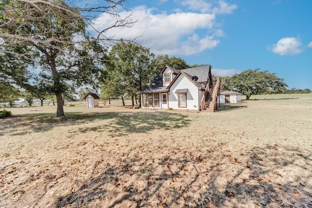 view of side of property with a rural view, a lawn, and a shed