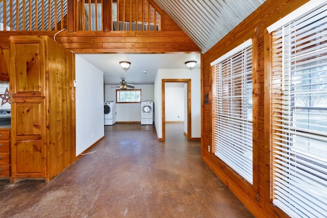 corridor with washer and clothes dryer, wood walls, a wealth of natural light, and vaulted ceiling