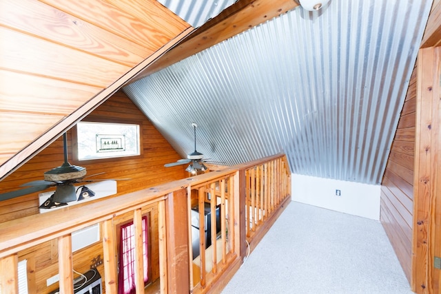 hallway featuring wood walls, vaulted ceiling, and carpet floors