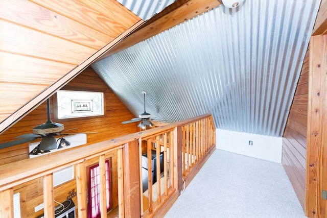 corridor featuring carpet flooring, vaulted ceiling, and wood walls