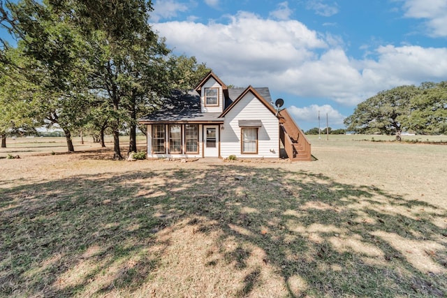 view of front of property featuring a front lawn and a rural view