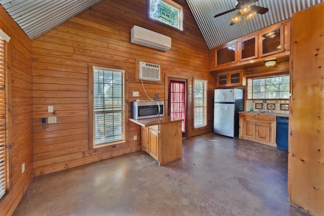 kitchen with stainless steel appliances, wood walls, an AC wall unit, and high vaulted ceiling