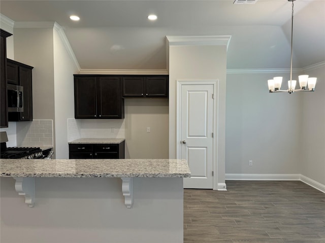 kitchen featuring light stone counters, decorative light fixtures, a breakfast bar, and range