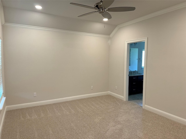 carpeted empty room featuring crown molding, vaulted ceiling, and ceiling fan