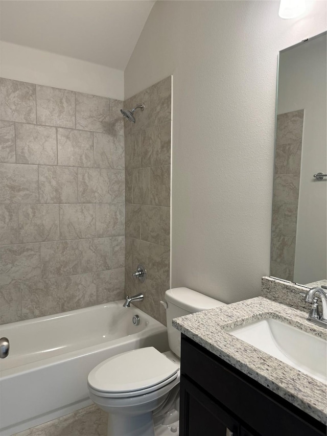 full bathroom featuring tiled shower / bath combo, vanity, vaulted ceiling, and toilet