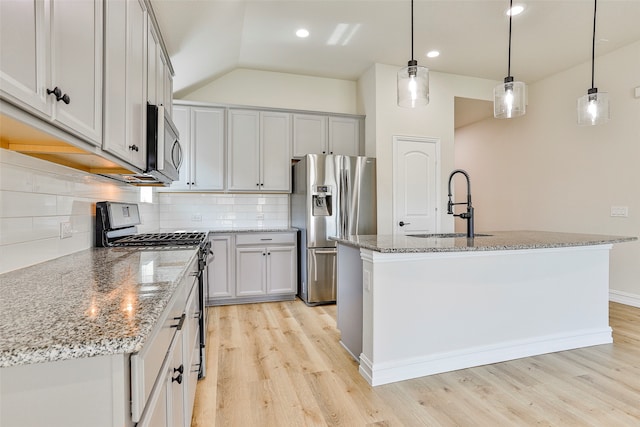 kitchen with tasteful backsplash, stainless steel appliances, a kitchen island with sink, light hardwood / wood-style flooring, and sink