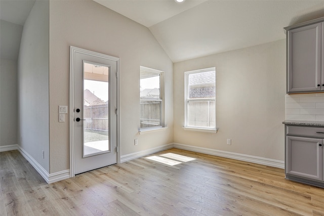 doorway with light wood-type flooring and vaulted ceiling