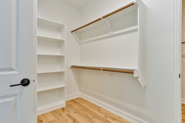 walk in closet with light hardwood / wood-style floors