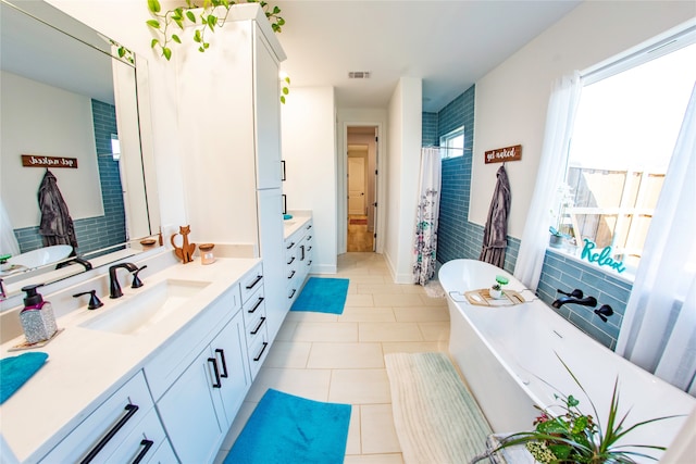 bathroom featuring tile patterned floors, vanity, and a bath