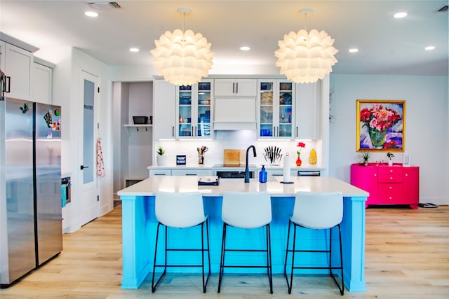 kitchen featuring backsplash, sink, light hardwood / wood-style floors, and stainless steel refrigerator