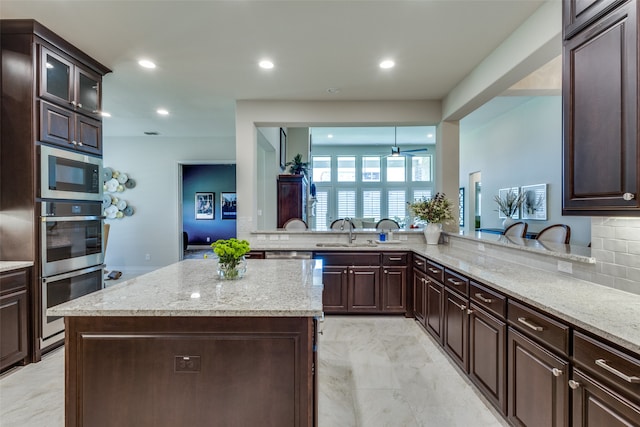 kitchen with light tile patterned flooring, stainless steel appliances, sink, and light stone countertops