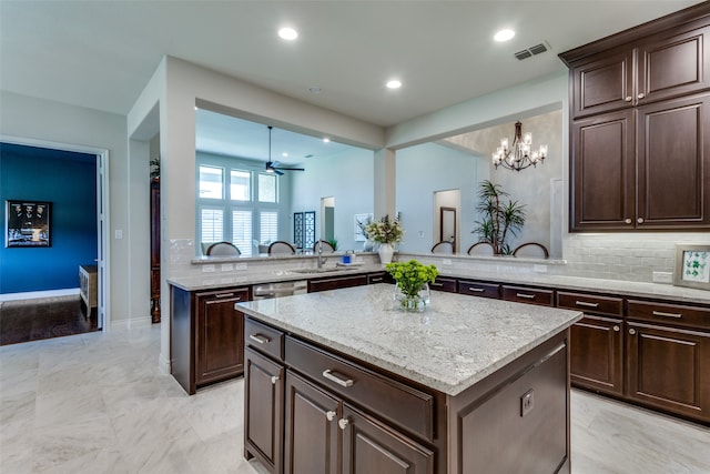 kitchen featuring ceiling fan with notable chandelier, kitchen peninsula, a center island, and decorative backsplash