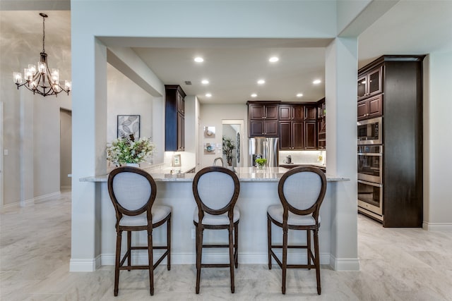 kitchen featuring light tile patterned flooring, stainless steel appliances, light stone counters, and kitchen peninsula