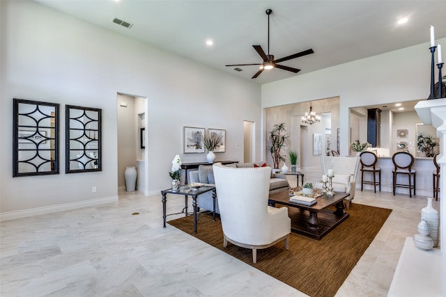 living room featuring light tile patterned flooring, ceiling fan with notable chandelier, and a high ceiling