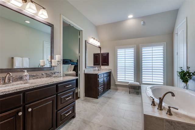 bathroom featuring double vanity, tiled tub, tile patterned floors, and lofted ceiling