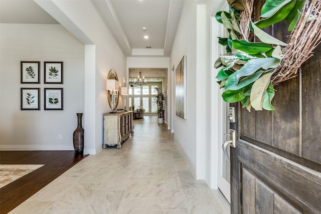 foyer entrance with baseboards and a notable chandelier