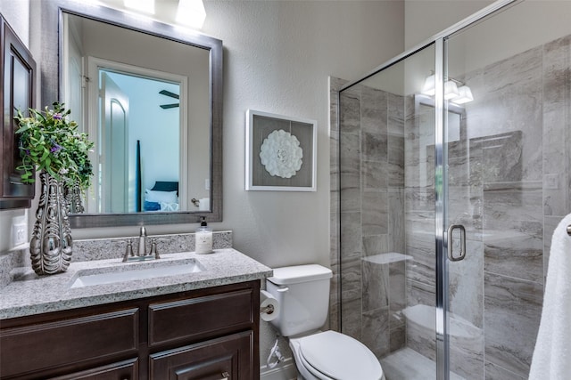 bathroom featuring a textured wall, a stall shower, vanity, and toilet