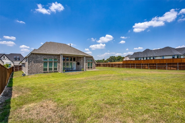 rear view of house with brick siding, a lawn, and a fenced backyard