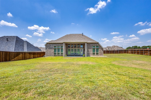 rear view of house featuring brick siding, a yard, a fenced backyard, and a patio