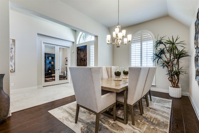 dining space with french doors, a chandelier, lofted ceiling, and hardwood / wood-style floors