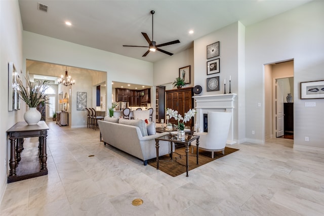 living room with light tile patterned floors, ceiling fan with notable chandelier, and a towering ceiling