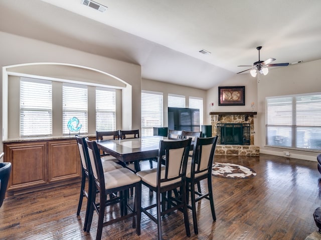 dining room featuring lofted ceiling, a stone fireplace, dark hardwood / wood-style floors, and ceiling fan