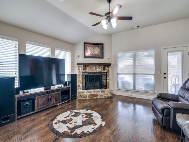 living room featuring ceiling fan, vaulted ceiling, a stone fireplace, and dark hardwood / wood-style floors