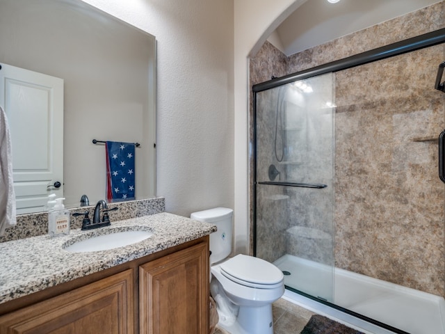 bathroom with vanity, walk in shower, toilet, and tile patterned flooring