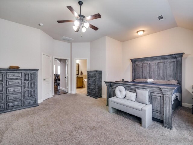 bedroom featuring ceiling fan, connected bathroom, vaulted ceiling, and light colored carpet