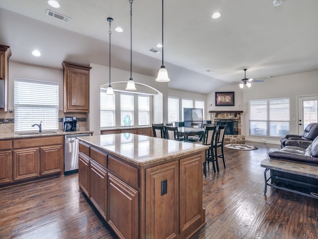 kitchen featuring a fireplace, dishwasher, backsplash, dark hardwood / wood-style floors, and a kitchen island