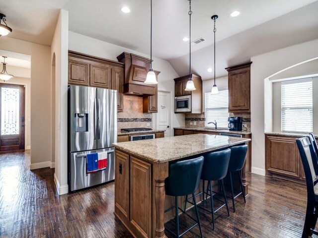 kitchen featuring custom exhaust hood, appliances with stainless steel finishes, dark wood-type flooring, tasteful backsplash, and a kitchen island