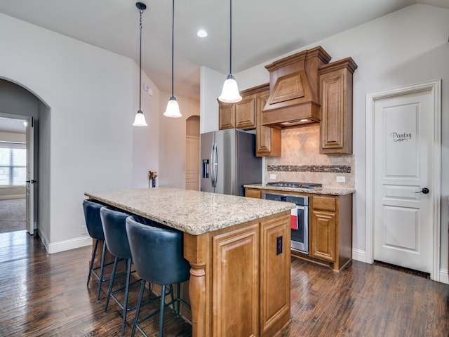 kitchen with decorative backsplash, dark hardwood / wood-style floors, stainless steel appliances, premium range hood, and a kitchen island