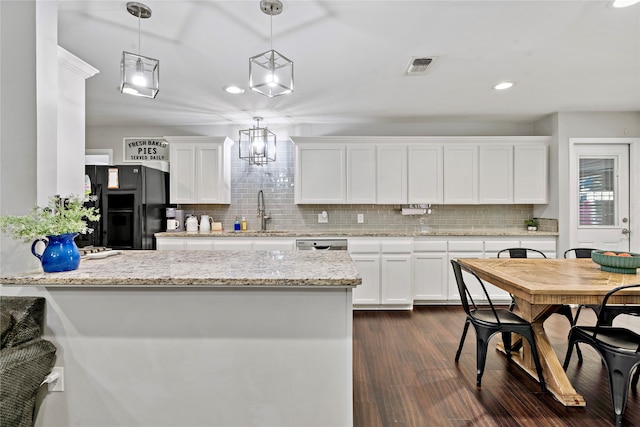 kitchen with pendant lighting, dark hardwood / wood-style floors, decorative backsplash, white cabinetry, and black refrigerator