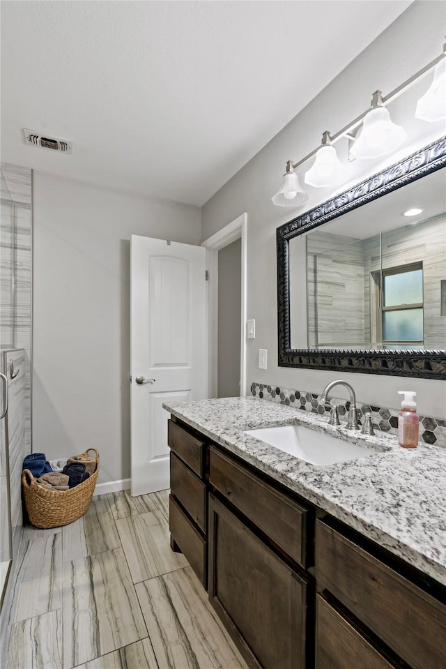 bathroom with a shower with door and vanity