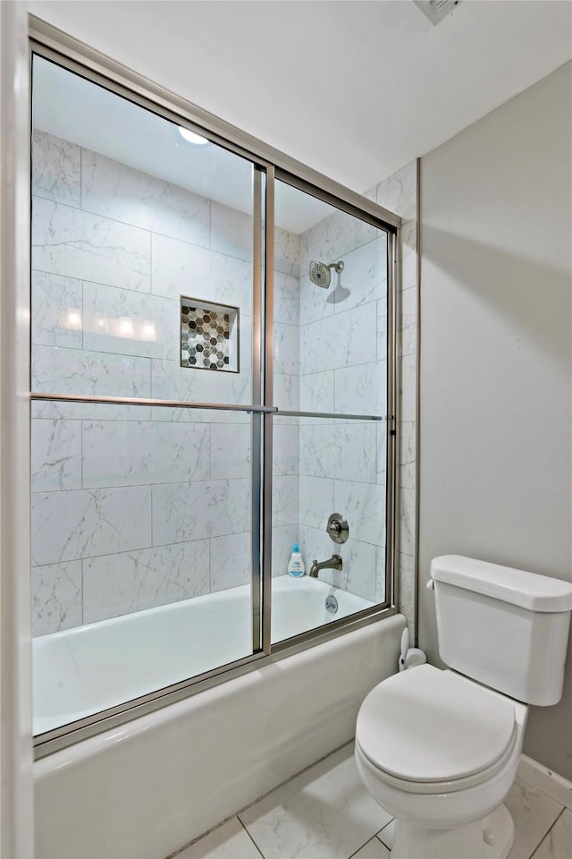 bathroom with toilet and shower / bath combination with glass door