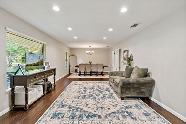 living room with a notable chandelier, a wealth of natural light, and dark hardwood / wood-style floors