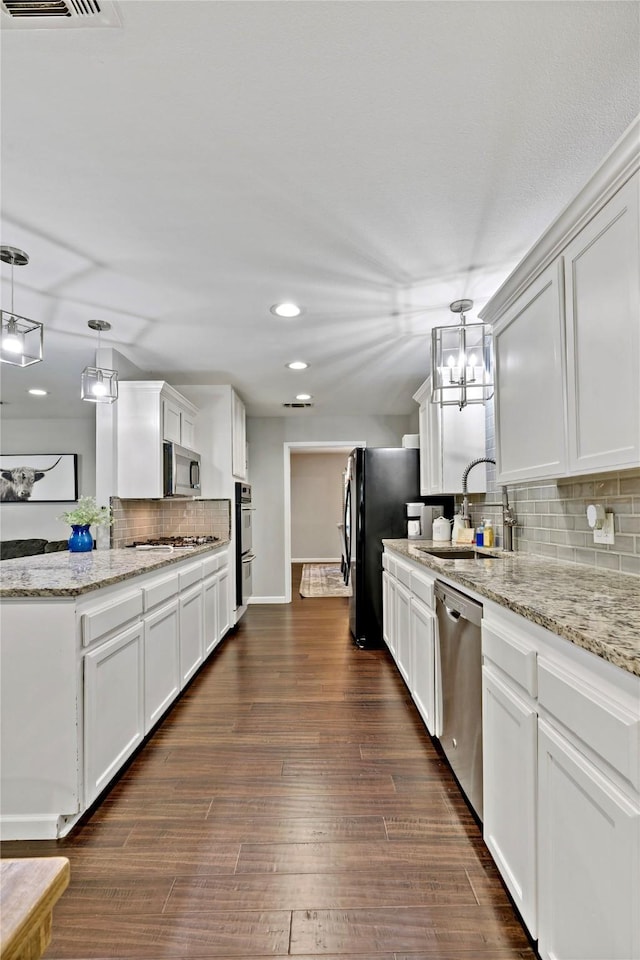 kitchen with appliances with stainless steel finishes, sink, hanging light fixtures, and white cabinets