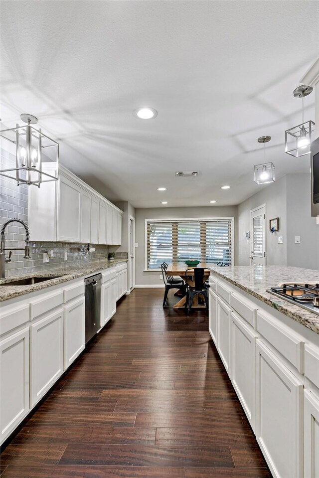 kitchen with light stone counters, dark hardwood / wood-style floors, white cabinets, decorative light fixtures, and stainless steel appliances