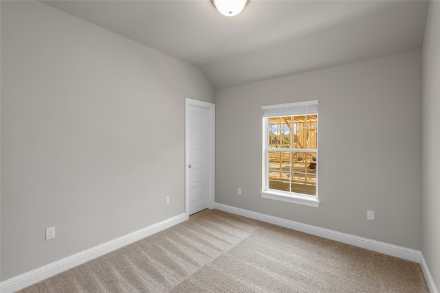 carpeted spare room featuring lofted ceiling