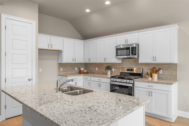 kitchen with a kitchen island with sink, decorative backsplash, appliances with stainless steel finishes, and sink