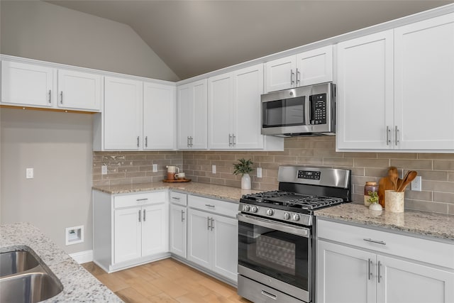 kitchen featuring tasteful backsplash, lofted ceiling, stainless steel appliances, and light hardwood / wood-style floors